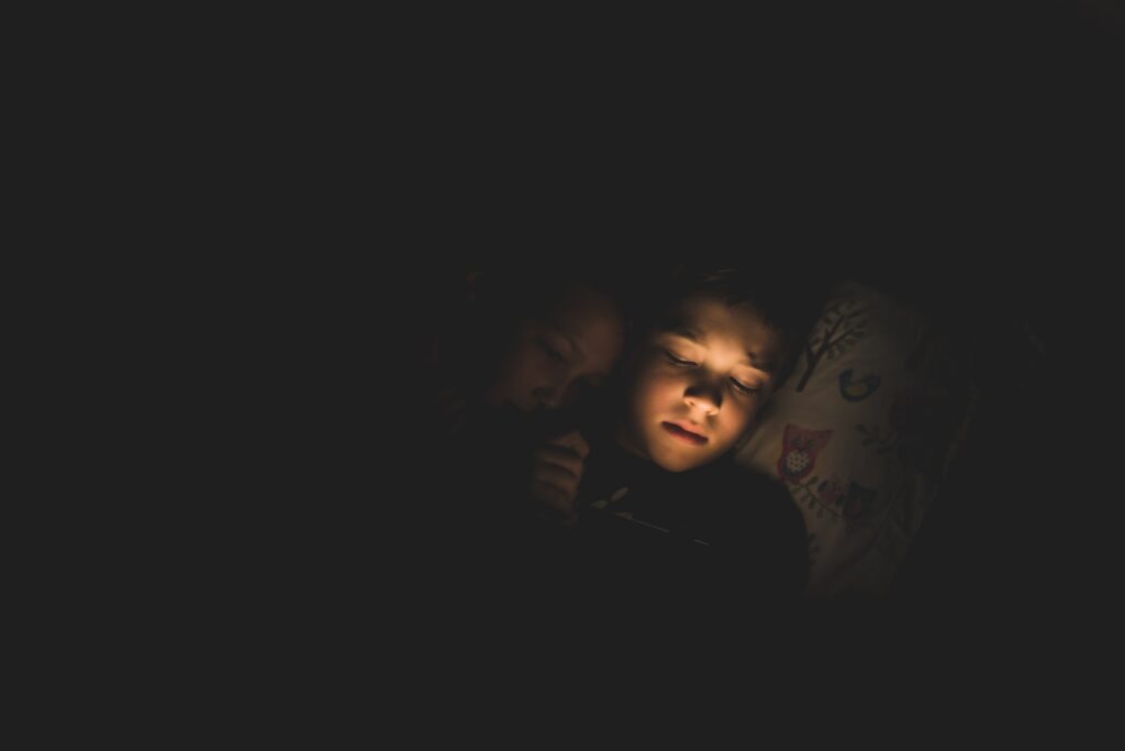 Dealing with Childhood Trauma in Adulthood. Image of two children on a bed in the dark.