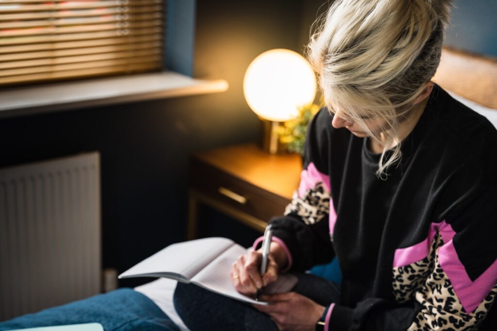 Blonde woman writing in notebook | The Method That Beats New Year's Resolutions