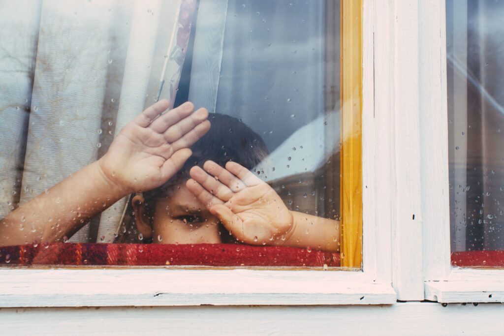 small boy at a window, with his hands against the glass